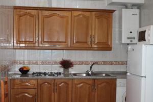 卡皮雷拉Apartamentos Rurales Rosendo: "Don Pedro de Noche"的厨房配有木制橱柜、水槽和冰箱。