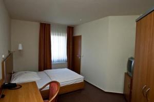 帕德博恩马努酒店 的一间卧室配有一张床、一张桌子和一台电视