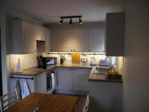 瓦斯代尔下城Scafell View Apartment, Wasdale, Lake District, Cumbria的厨房配有白色橱柜和木桌