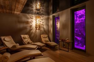 采尔马特22 Summits Boutique Hotel的配有椅子和紫色灯的理疗室