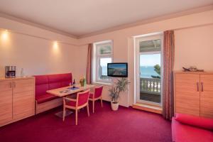 宾茨Strandhotel zur Promenade的一间设有红色沙发、桌子和窗户的客房