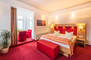 宾茨Strandhotel zur Promenade的酒店客房,配有一张床和两张红色椅子