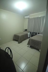 DianópolisMosaico Hotel的一间带两张床的卧室,铺有瓷砖地板。