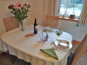 班科里Bridge of Bennie Cottage的一张桌子,上面放着一瓶葡萄酒和一瓶鲜花