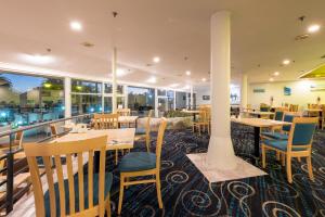 派西亚国敦大酒店&度假村 - 岛屿湾的餐厅设有木桌、椅子和窗户。