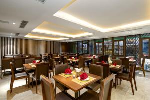 岘港Palazzo 3 Danang Hotel的一间在房间内配有桌椅的餐厅