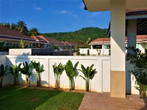 华欣Villa de Veluwe @ Hua Hin的房屋前有棕榈树的白色围栏