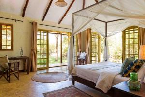 阿鲁沙Kili Villa Kilimanjaro Luxury Retreat的一间卧室配有一张大天蓬床和一张书桌