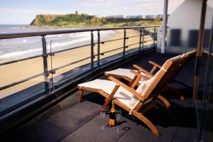 斯卡伯勒金沙酒店的俯瞰海滩的阳台提供两把椅子和一瓶啤酒