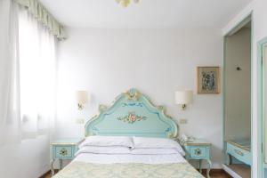 威尼斯瑟瑞尼斯玛酒店的一间卧室配有一张带蓝色床头板的床和两张桌子