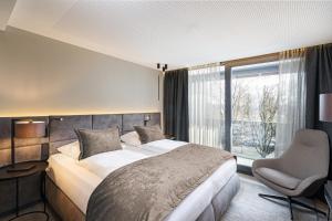 巴特法兴格Hotel Riedenburg的卧室配有床、椅子和窗户。