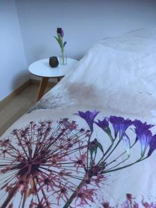 奥德纳尔德Annex的一张床上,上面有紫色花卉,上面有白色的毯子