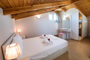 苏卡雷斯Lefkogea Villas & Apartments的卧室设有白色的床和木制天花板。