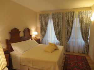 维罗纳卡萨潘维尼奥酒店的一间卧室配有一张带白色床单和窗帘的床