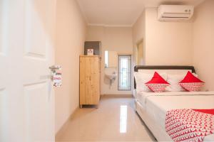 雅加达OYO 387 Alfa Guest House的一间卧室配有一张带红色枕头的床