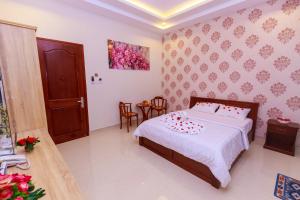 芹苴万乐酒店的一间卧室配有带白色床单和红色枕头的床。