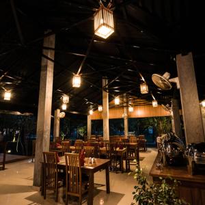 锡吉里亚Sigiri Asna Nature Resort的餐厅设有木桌和椅子及灯