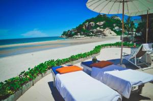 华欣乃恩夏洛特海滨酒店的海滩配有两张床和一把遮阳伞