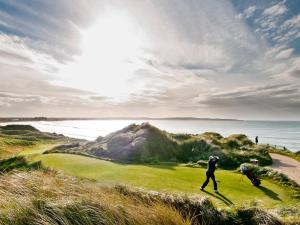 敦贝格Trump International Golf Links & Hotel Doonbeg Ireland的两人在附近的高尔夫球场打高尔夫