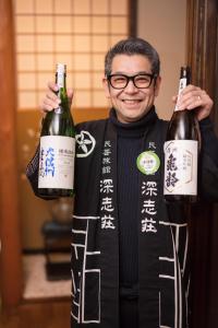 松本富卡式艘酒店的拿着两瓶葡萄酒的人
