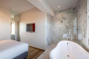根特卡尔顿酒店的白色的浴室设有浴缸和床。
