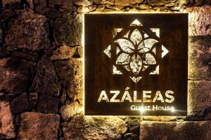 Ribeira ChãAzaleas Guest House的石墙上的探险房屋标志