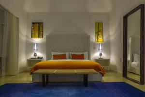 安东尼奥港三叉戟酒店 的一间卧室配有带橙色床单和镜子的床