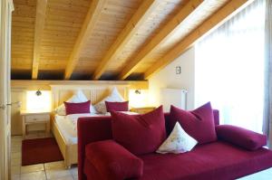 施万高谷咕霍夫乡村酒店的一间卧室配有红色沙发及枕头