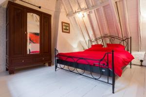 根特Romantic 16th century workers house的一间卧室配有一张带红色枕头和镜子的床