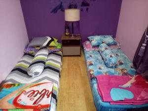 万隆Homestay Syariah Cileunyi, Bandung Timur的紫色墙壁客房的两张床