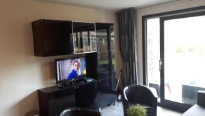 霍勒姆Fijn en gezellig App TIME-OUT, beg grond, Prive TERRAS, eigen KEUKEN, Dichtbij Strand en Vuurtoren, Incl verwarmd Hotel-ZWEMBAD的客厅配有平面电视和窗户。