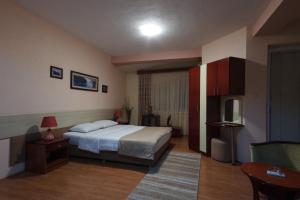 斯特鲁米察伊林登酒店的一间卧室配有一张床、一张桌子和一台电视。