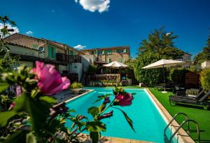 于泽斯LOGIS HOTEL RESTAURANT L' Auberge d'Uzes的鲜花庭院中的游泳池