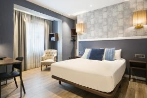 巴塞罗那阿卡德壮丽酒店的一间卧室配有一张床、一张桌子和一把椅子
