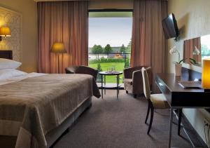 特拉凯Margis Hotel & SPA的配有一张床、一张书桌和一扇窗户的酒店客房
