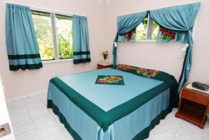 拉罗汤加日天堂海滩简易别墅酒店的一间卧室配有一张带蓝色床单和窗户的床。