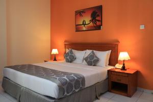 沙迦Al Maha Regency Hotel Suites - Managed by Aoudi Consultants的一间卧室配有一张带橙色墙壁的床和两盏灯。
