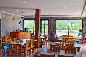 盼武里KP山海滩酒店的餐厅设有木桌、椅子和窗户。