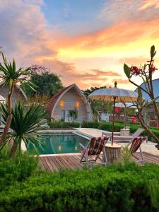 珀尼达岛La Roja Bungalows的一个带两把椅子和遮阳伞的游泳池