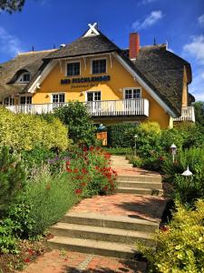 阿伦斯霍普Der Fischländer Garni的黄色房子,有茅草屋顶和鲜花