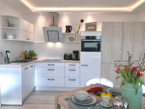 宾茨Villa Heinrich的厨房配有白色橱柜和一张带餐具的桌子。