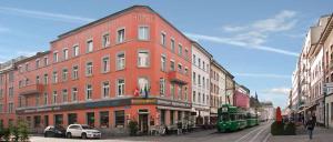 巴塞尔莱茵霍夫酒店的一条城市街道上的红色大建筑,有一辆公共汽车