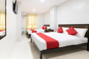 马尼拉OYO 152 Sangco Condotel的两张位于酒店客房的床铺,配有红色枕头