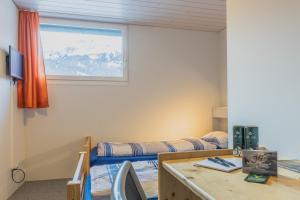伦克Mountain Lodge Backpackercamp的一间卧室配有一张床、一张书桌和一个窗户。