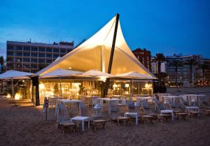 卡里拉Hotel Bernat II 4*Sup的海滩上晚上的一组椅子和遮阳伞