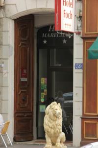 里昂富驰酒店的狮子雕像坐在建筑物前