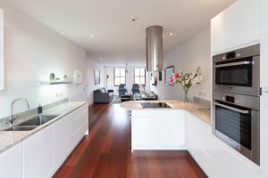 温莎Hampden Apartments - The Charles的一间带白色橱柜的厨房和一间客厅