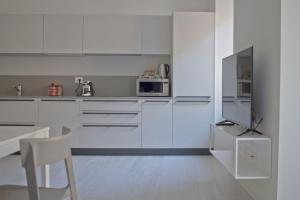 特伦托Casa Bacca apartments的白色的厨房配有白色橱柜和电视。