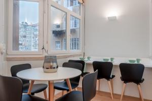里斯本NLC Rooms & Suites的客房设有桌椅和窗户。