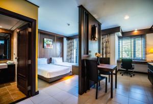 拉威海滩Ratana Hotel Chalong的配有一张床、一张桌子和一张桌子的酒店客房